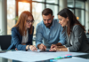 Trois personnes collaborent autour d'un plan dans un bureau lumineux
